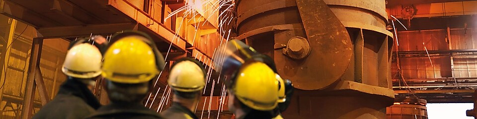 ouvriers observant une machine dans une usine de métallurgie