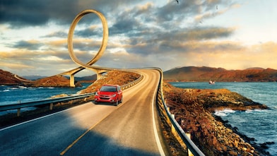 Red car driving on the road by the river