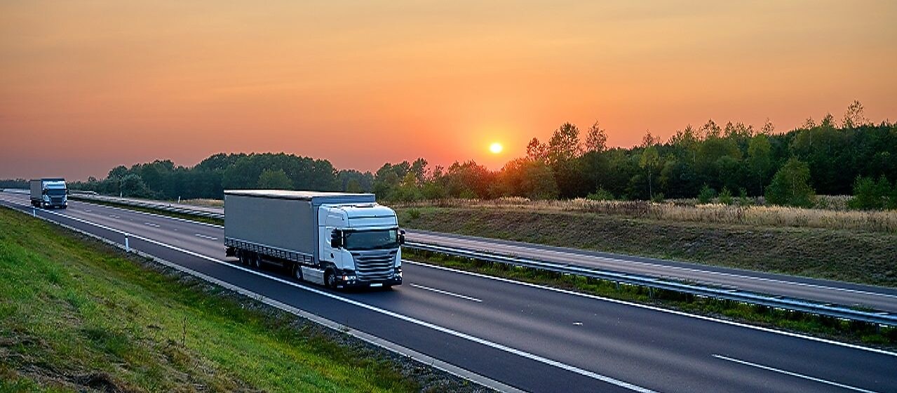 Trucks on a highway at sunset