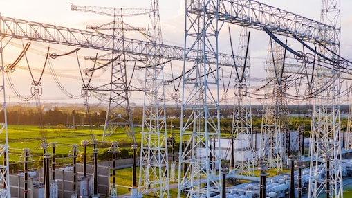 Transformatorstation met onderling verbonden hoogspanningsleidingen en apparatuur bij zonsondergang.
