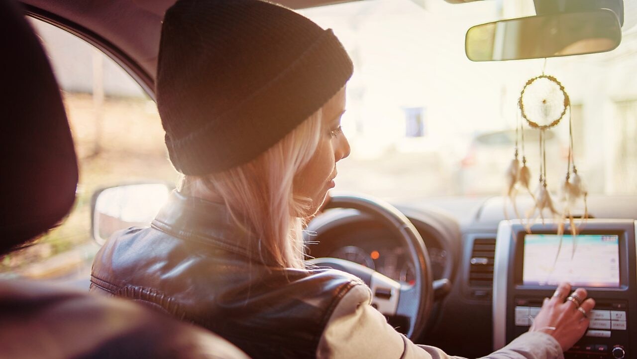 Une jeune femme consulte les instructions du GPS de sa voiture